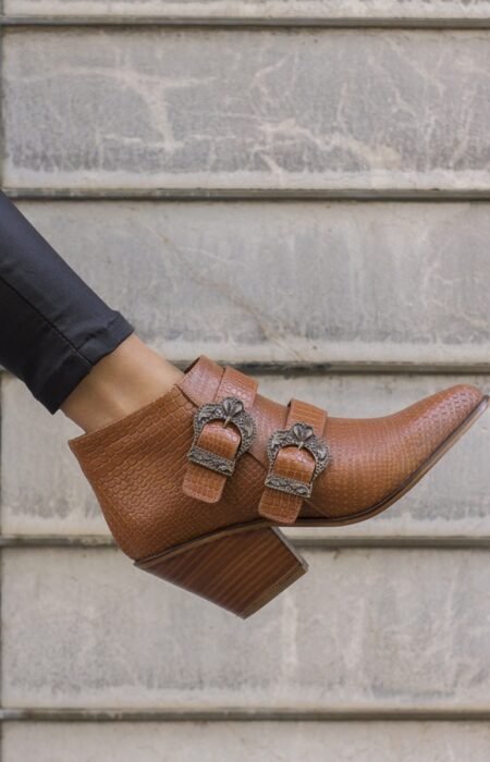 A fashionable woman wearing a crocodile patterned brown elegant heel decorated with belts