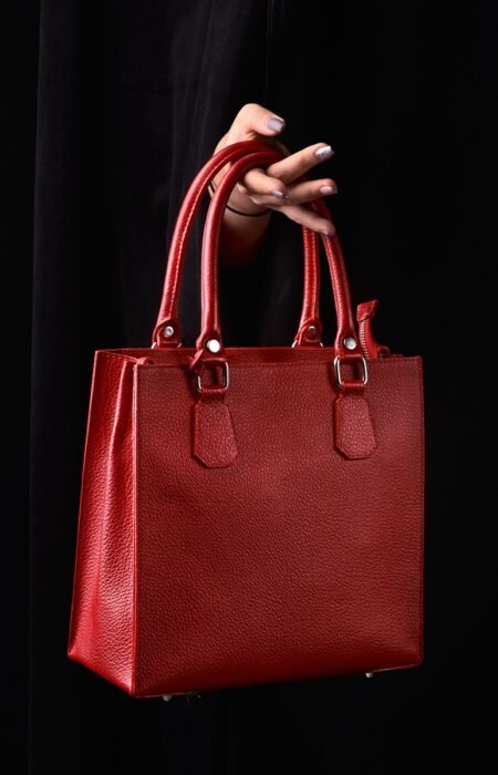 Modern red leather bagin a female hand. 1:1 copy space for text and design. Accessory, studio shot.